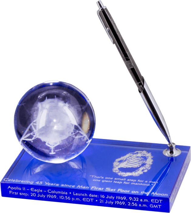 AG7-45LE Apollo 11 45th Anniversary Astronaut Space Pen, Limited Edition Space Pen in the pen holder of the paperweight. The base of the paperweight is blue and is etched with a footprint of the astronauts left on the moon, the mission's dates and times,